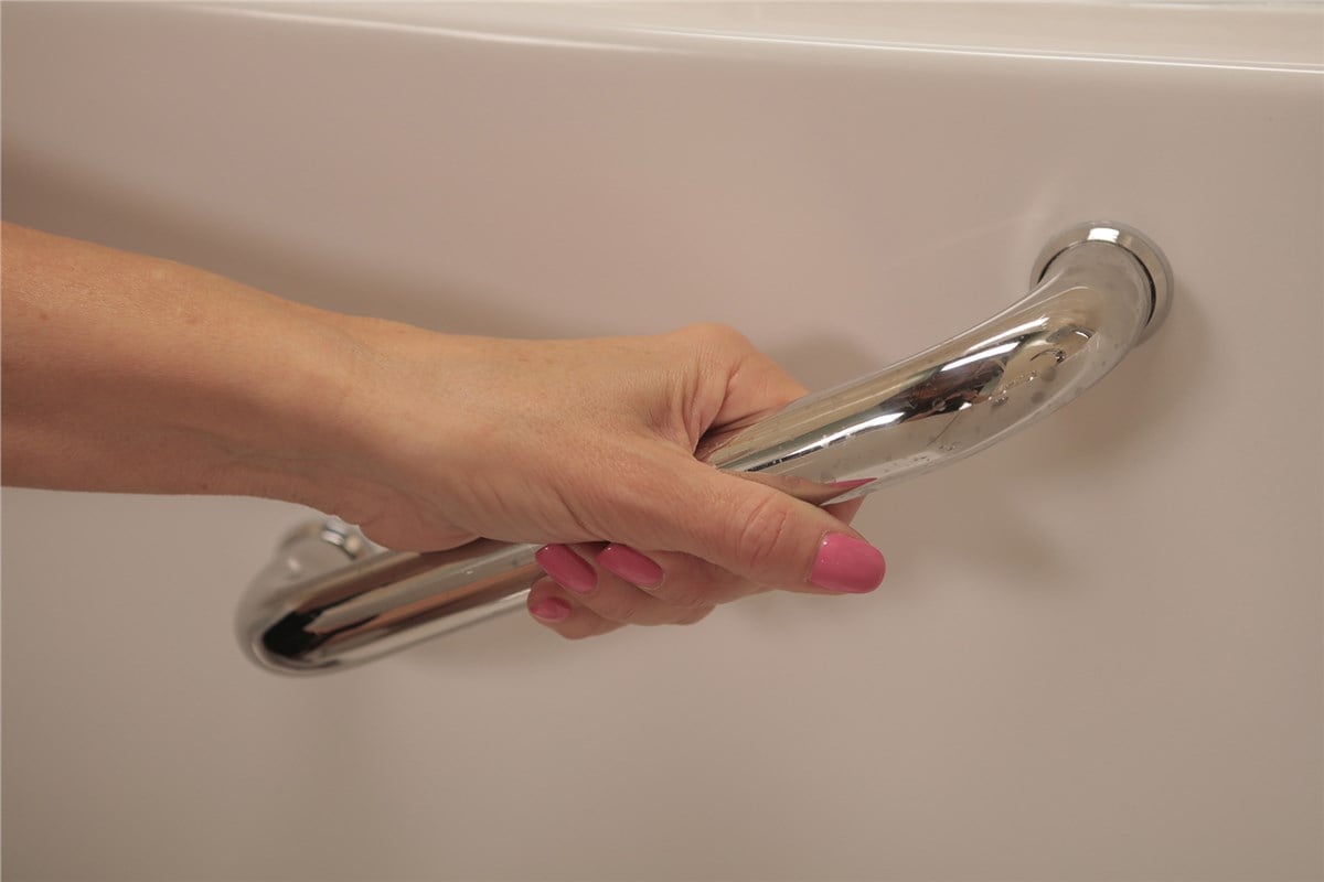 Hand gripping a chrome safety grab bar on a bathtub for bathroom accessibility