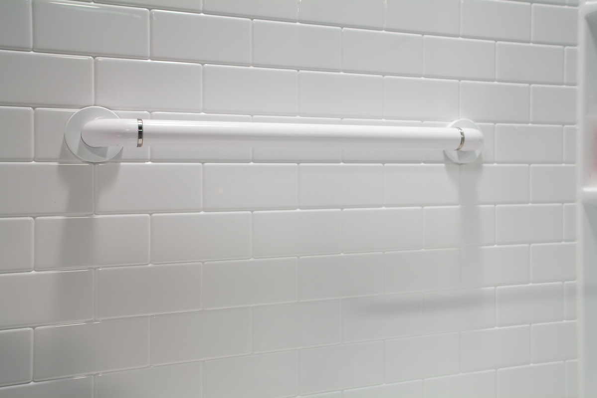 White straight grab bar on white subway tile wall