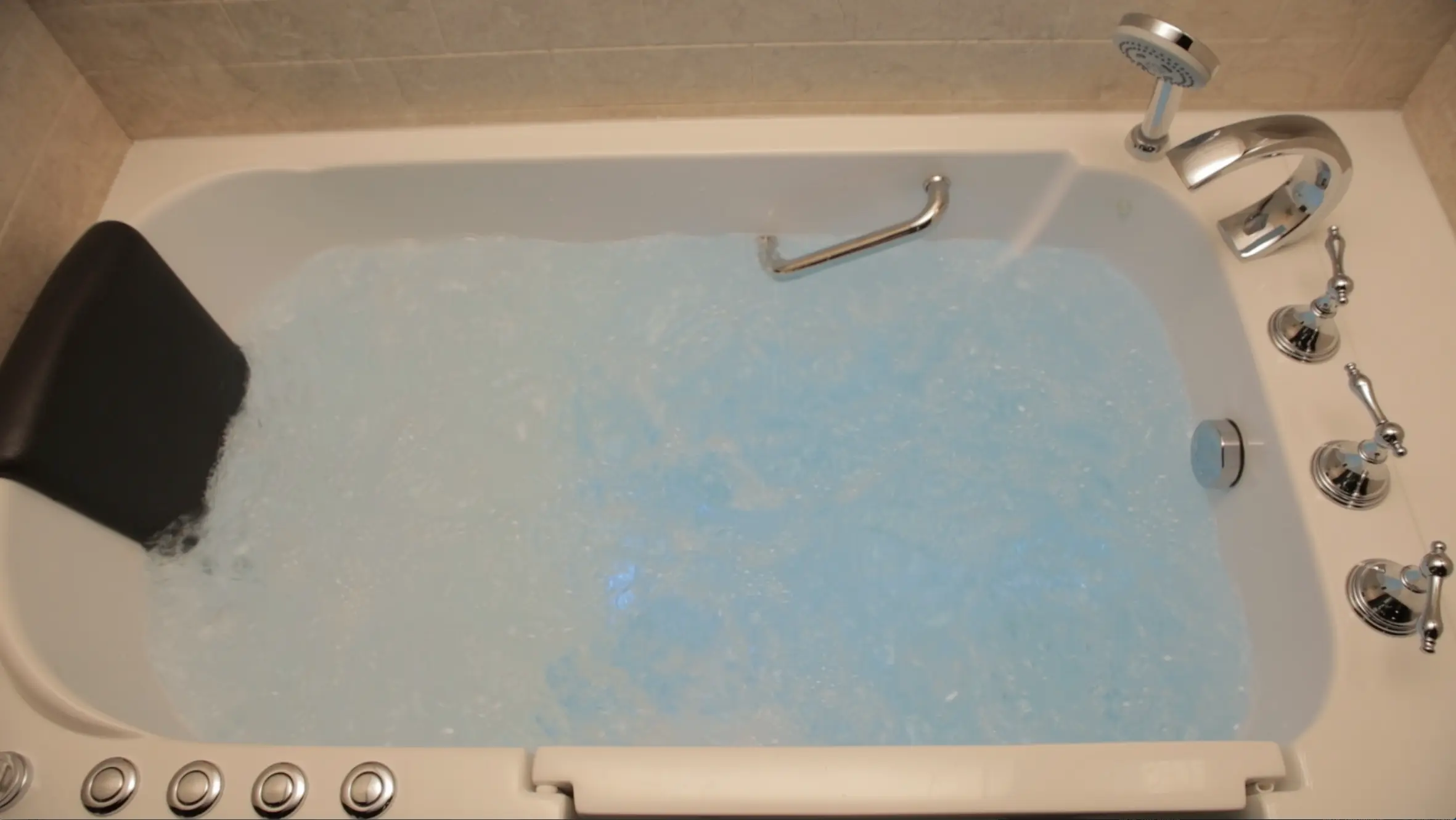 Walk-in tub with blue jets running and chrome fixtures