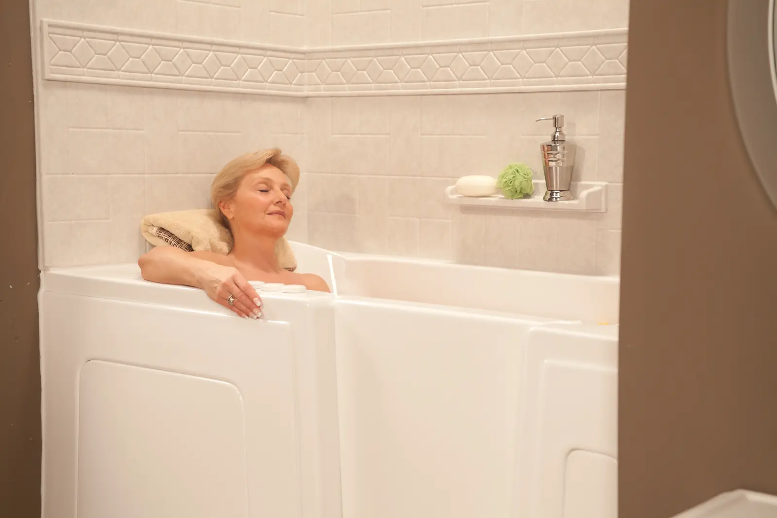 Woman relaxing in walk-in tub with roman stone windmill tile and listello trim